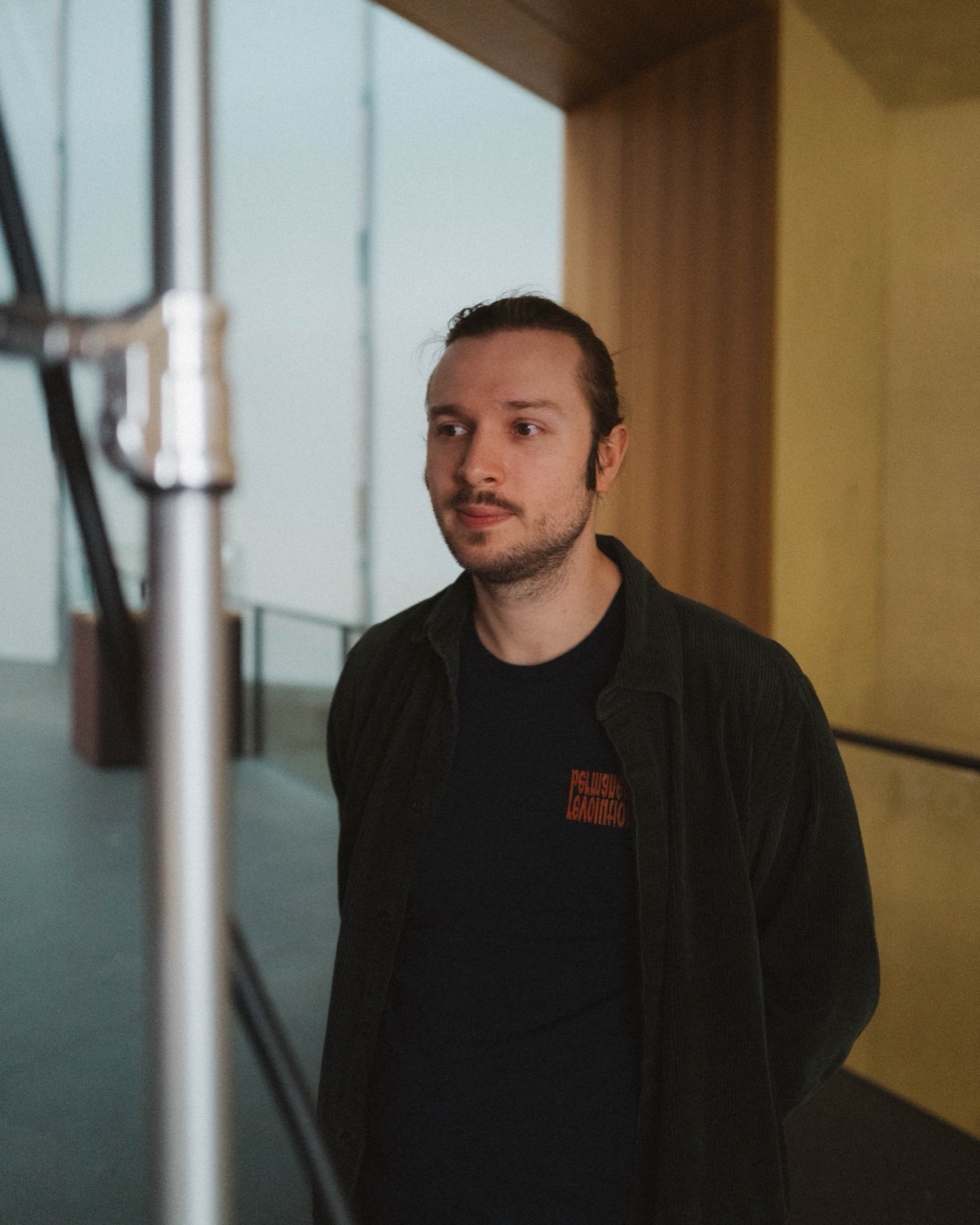 Porträt von Gleb Lasarew im Gang eines Betongebäudes, den Blick zur Seite gerichtet.