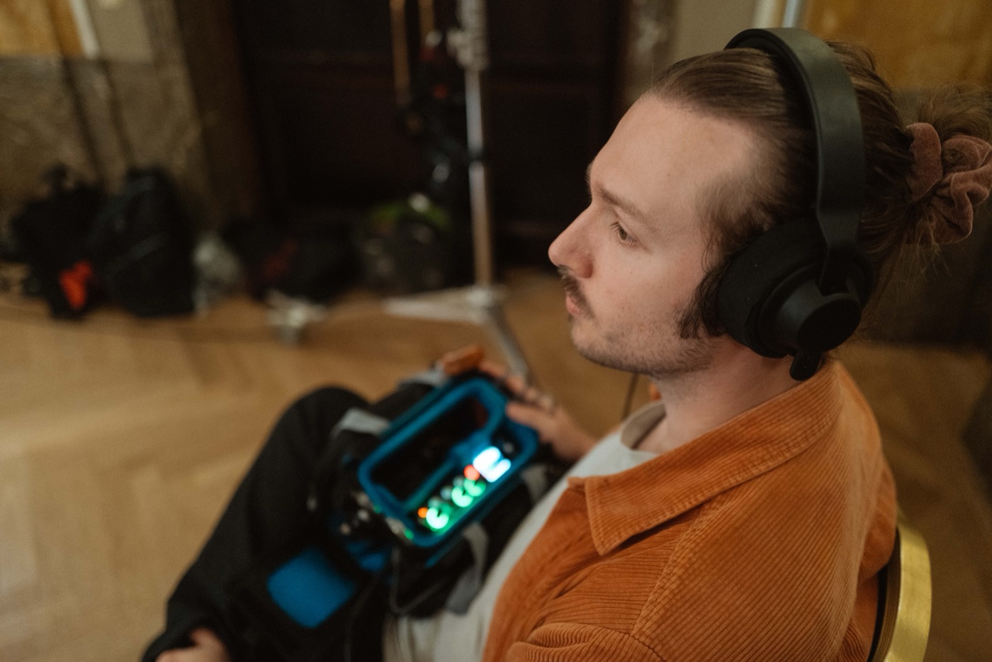 Gleb Lasarew im Profil mit Kopfhörern, der Mischer-Recorder leuchtet in der Tasche auf seinem Schoß.
