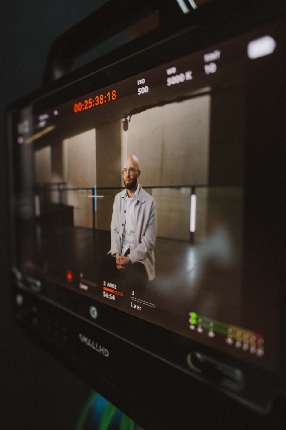 Kameramonitor mit laufendem Timecode, im Bild der Interviewgast.